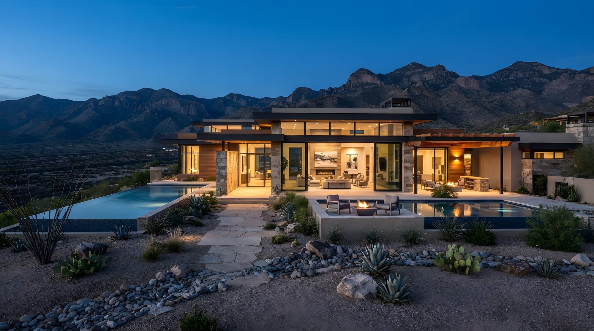 Modern single-storey home at dusk with warm interior light and mountains behind